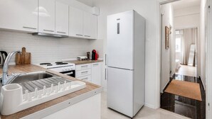 A modern kitchen with white cabinetry, a stainless steel refrigerator, and a built-in oven. - Phos Residence by Rentals Pro - Neos Marmaras Halkidiki (Neos Marmaras)