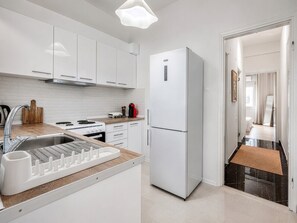 Eine moderne Küche mit weißen Schränken, einem Edelstahl-Kühlschrank und einem eingebauten Backofen.