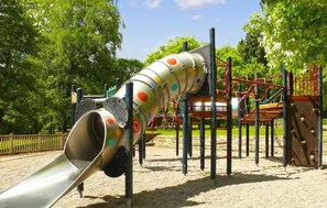 A playground with a slide, climbing structures, and a fenced area. - 1 bedroom amazing apartment in La Bourboule (La Bourboule)