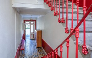 Ein Flur mit einer roten Treppe, einem gemusterten Boden und einer Tür, die zu einem Außenbereich führt.