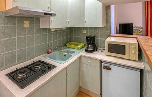 Eine kompakte Küche mit Gasherd, Mikrowelle, Kaffeemaschine und Geschirrspüler.