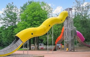 Ein Spielplatz mit einer gelben Rutsche, einer roten Rutsche und einer Kletterkonstruktion.