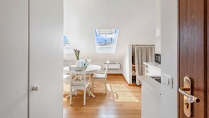 A room with a dining table, chairs, a window with a view, and a door leading to another room. - Central Loft Sestri Levante (Sestri Levante)