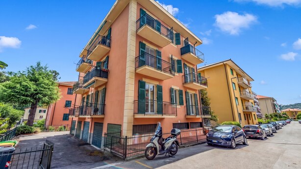 A multi-story residential building with balconies, parked cars, and a clear sky. - Central Loft Sestri Levante (Sestri Levante)