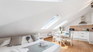 A modern loft bedroom with a skylight, a dining area, and a kitchenette. - Central Loft Sestri Levante (Sestri Levante)