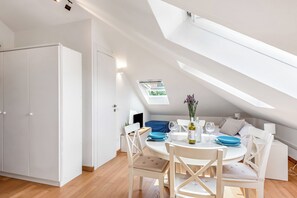 A modern, well-lit room with a skylight, a dining table with chairs, and a bed with a blue cover. - Central Loft Sestri Levante (Sestri Levante)