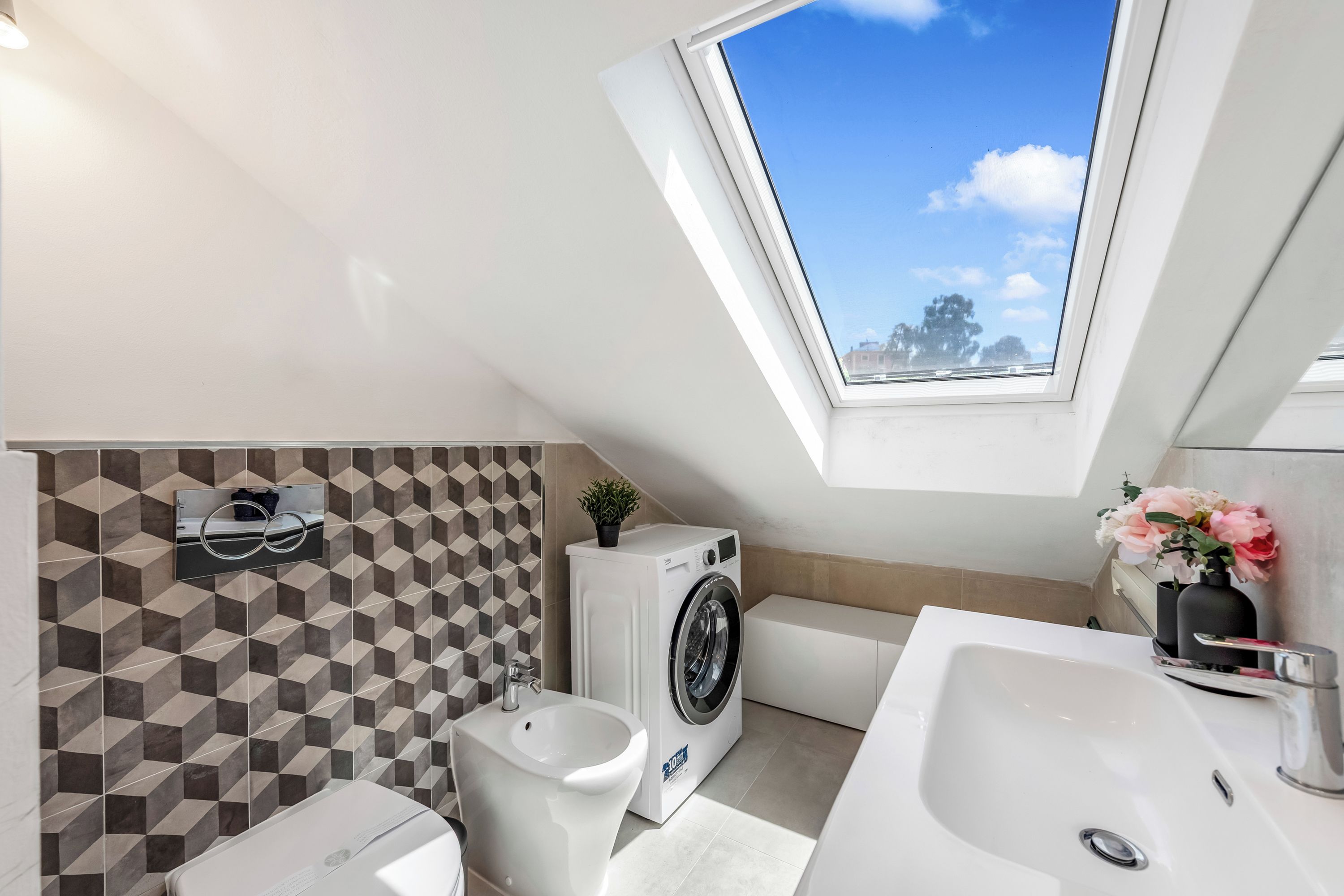 Une salle de bain moderne avec un puits de lumière, un lave-linge et un évier.