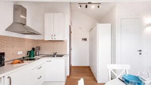 A modern kitchen with white cabinets, a stainless steel range hood, a tiled backsplash, and a wooden floor. - Central Loft Sestri Levante (Sestri Levante)