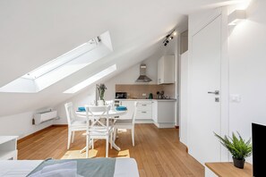 A modern loft bedroom with a skylight, a dining area, and a kitchenette. - Central Loft Sestri Levante (Sestri Levante)