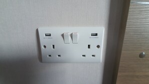 A white electrical outlet with two switches and two USB ports on a textured wall.