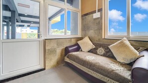 A room with a sofa, a window, and a door.