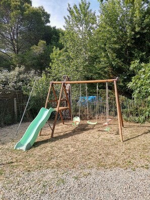 Ein Spielplatz mit Rutsche, Schaukeln und einer Kletterkonstruktion.