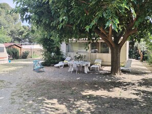 Eine Terrassenfläche mit Tisch und Stühlen, ein kleiner Garten und ein Gebäude im Hintergrund.