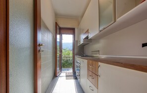 Una cucina stretta con mobili in legno, un lavello in acciaio inossidabile e vista su un balcone con una porta che dà sull'esterno.