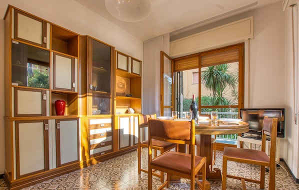 Una habitación con una mesa redonda, sillas, un televisor y vistas a zonas verdes.