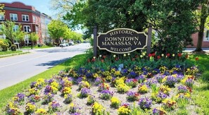 A historic downtown Manassas, VA welcome sign surrounded by a garden of colorful flowers.