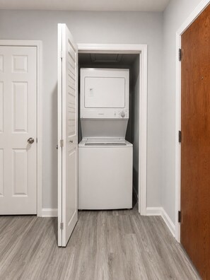 A laundry room with a washer and dryer, a white door, and a wooden door.