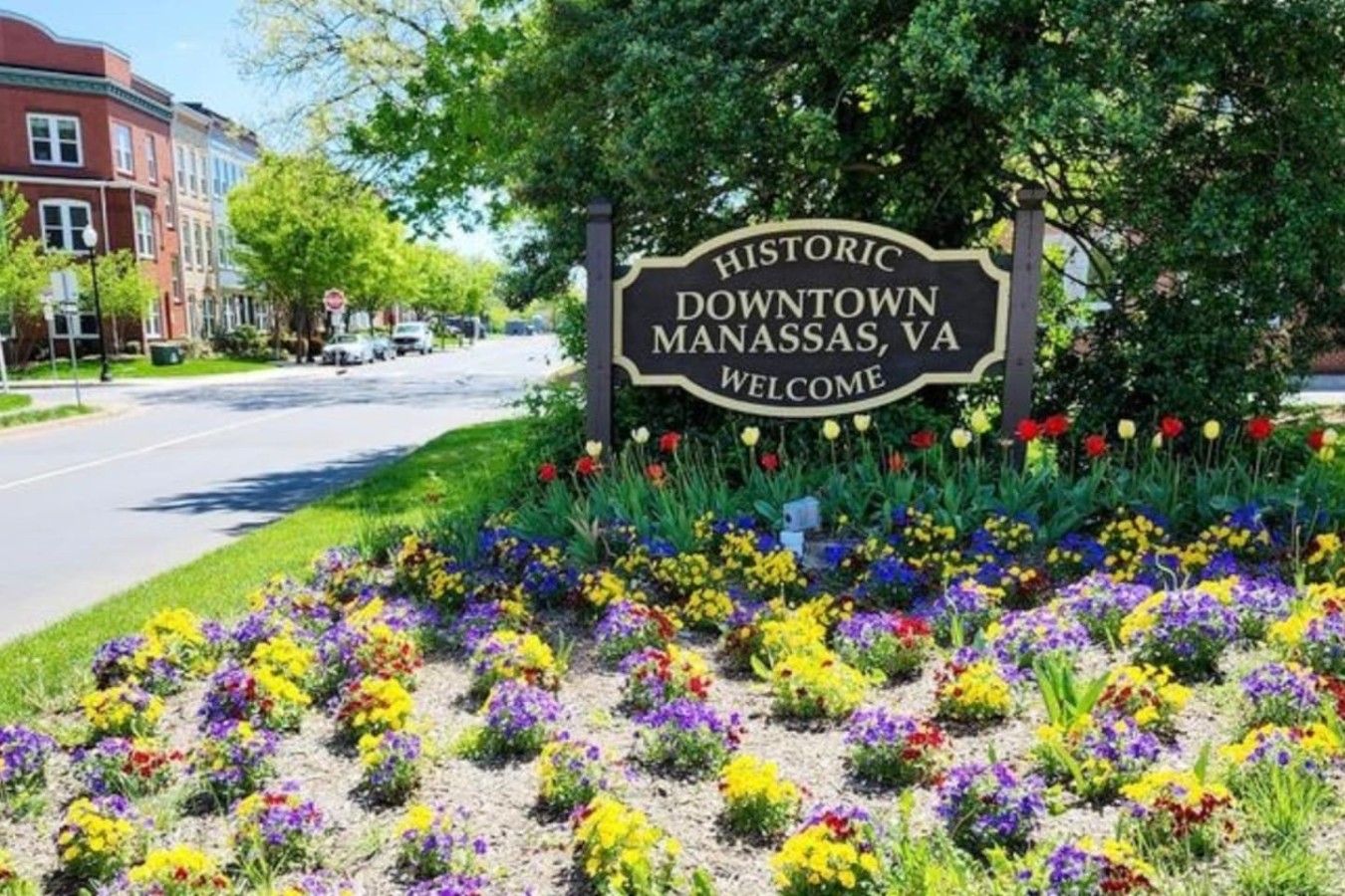A historic downtown welcome sign surrounded by a colorful flower bed.