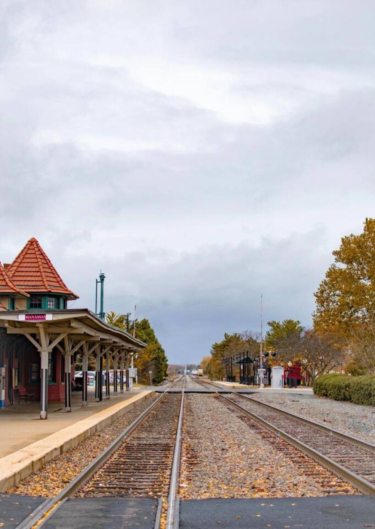 A train station with a covered waiting area and tracks.