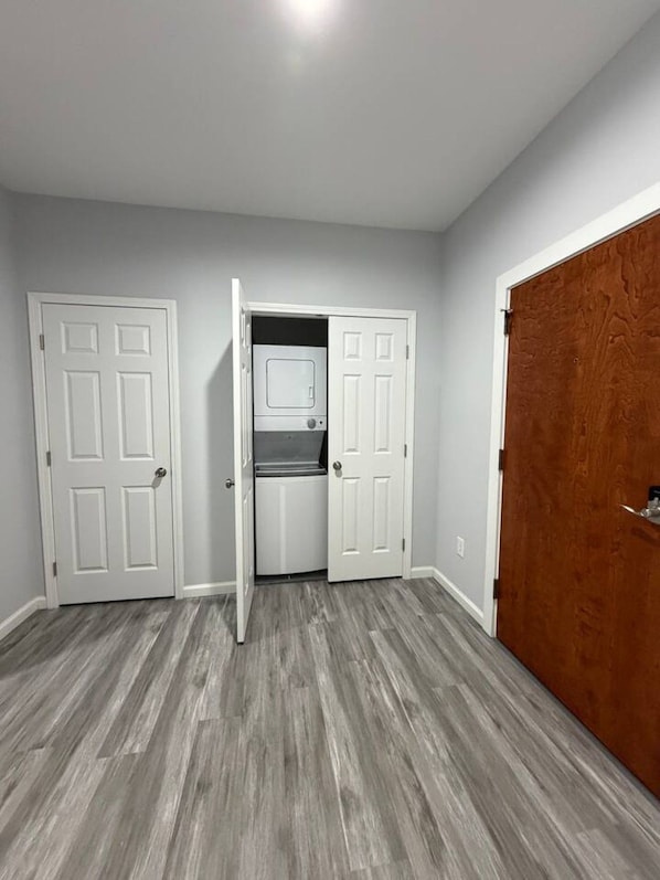 A hallway with two white doors, one leading to a laundry room with a washer and dryer, and another to a wooden closet.