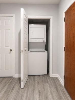 A laundry room with a washer and dryer, a white door, and a wooden door.