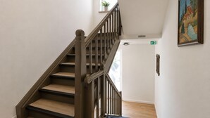 A staircase with wooden steps and a handrail, leading to a door with an emergency exit sign. - Zum Rheinberg - City Studio (Braubach)