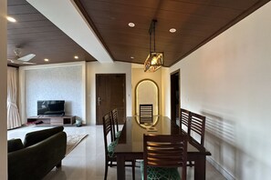 A modern dining area with a glass-top table, wooden chairs, and a ceiling fan. - 2BR Apartment Khaira Gali Murree Sleep 6 (Khaira Gali)
