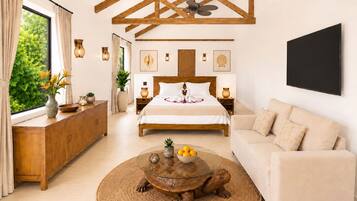 A modern hotel room with a large bed, a round coffee table with a turtle centerpiece, a sofa, and a large window with curtains.