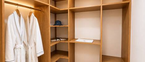 A walk-in closet with wooden shelving, a robe rack, and a pair of slippers.