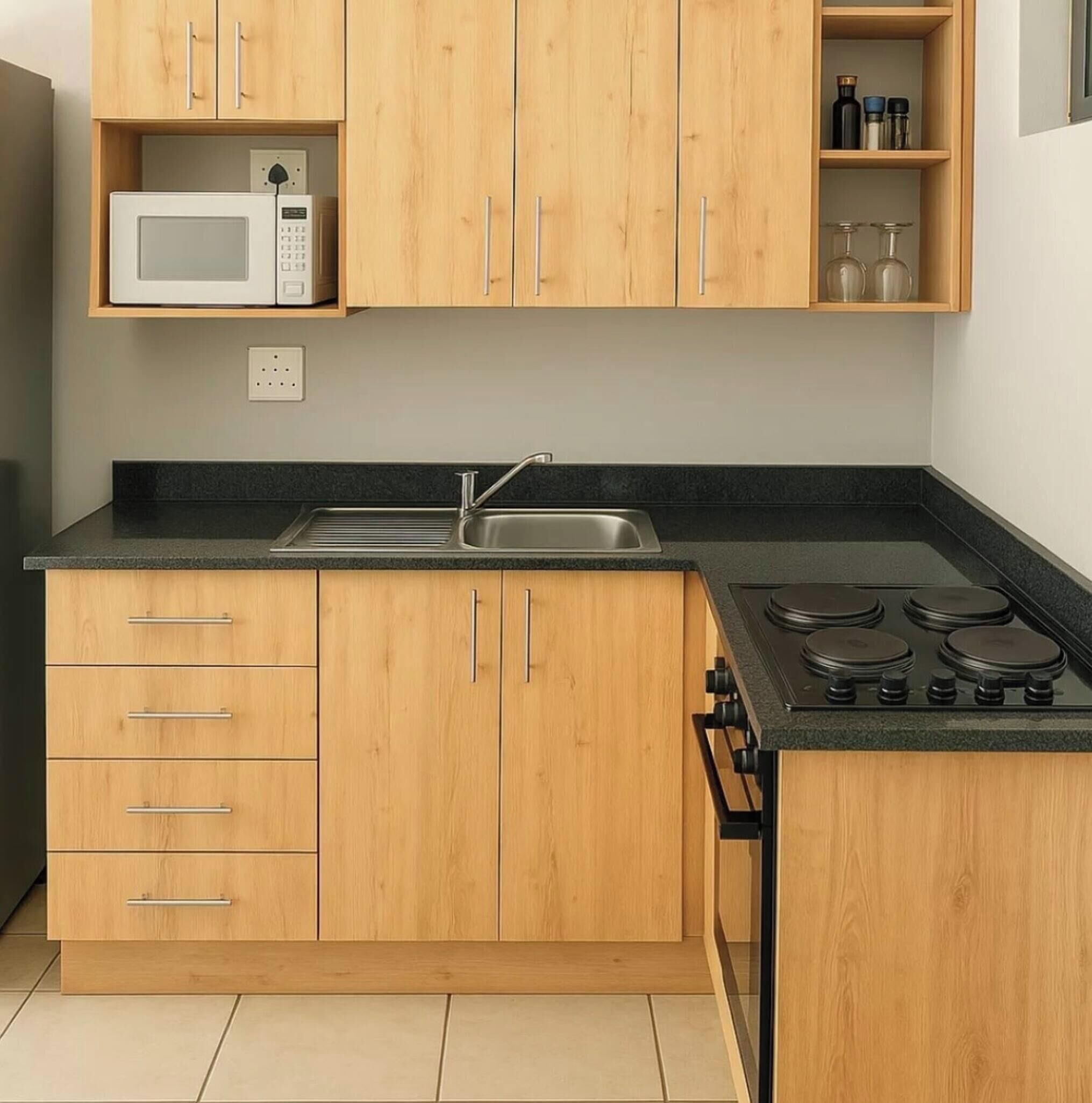 A kitchen with wooden cabinets, a microwave, a sink, and a stove.