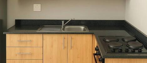A kitchen with wooden cabinets, a microwave, a sink, and a stove.