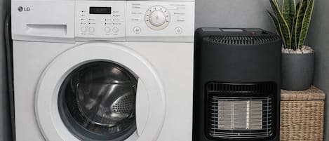 A compact laundry area with a front-loading washing machine, a dryer, and a small heater unit.