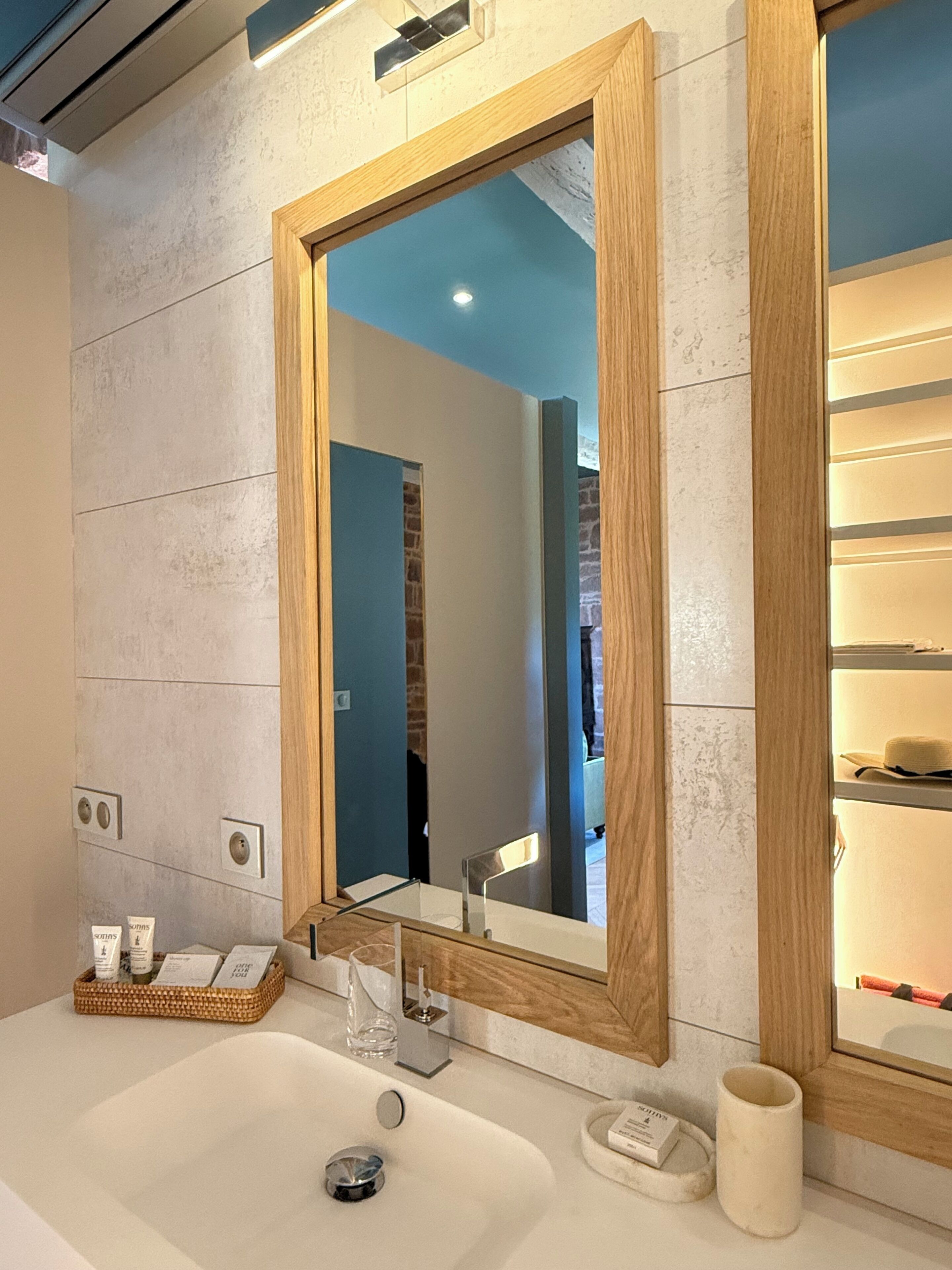 Un baño con un espejo grande, un lavamanos y un perchero para toallas.