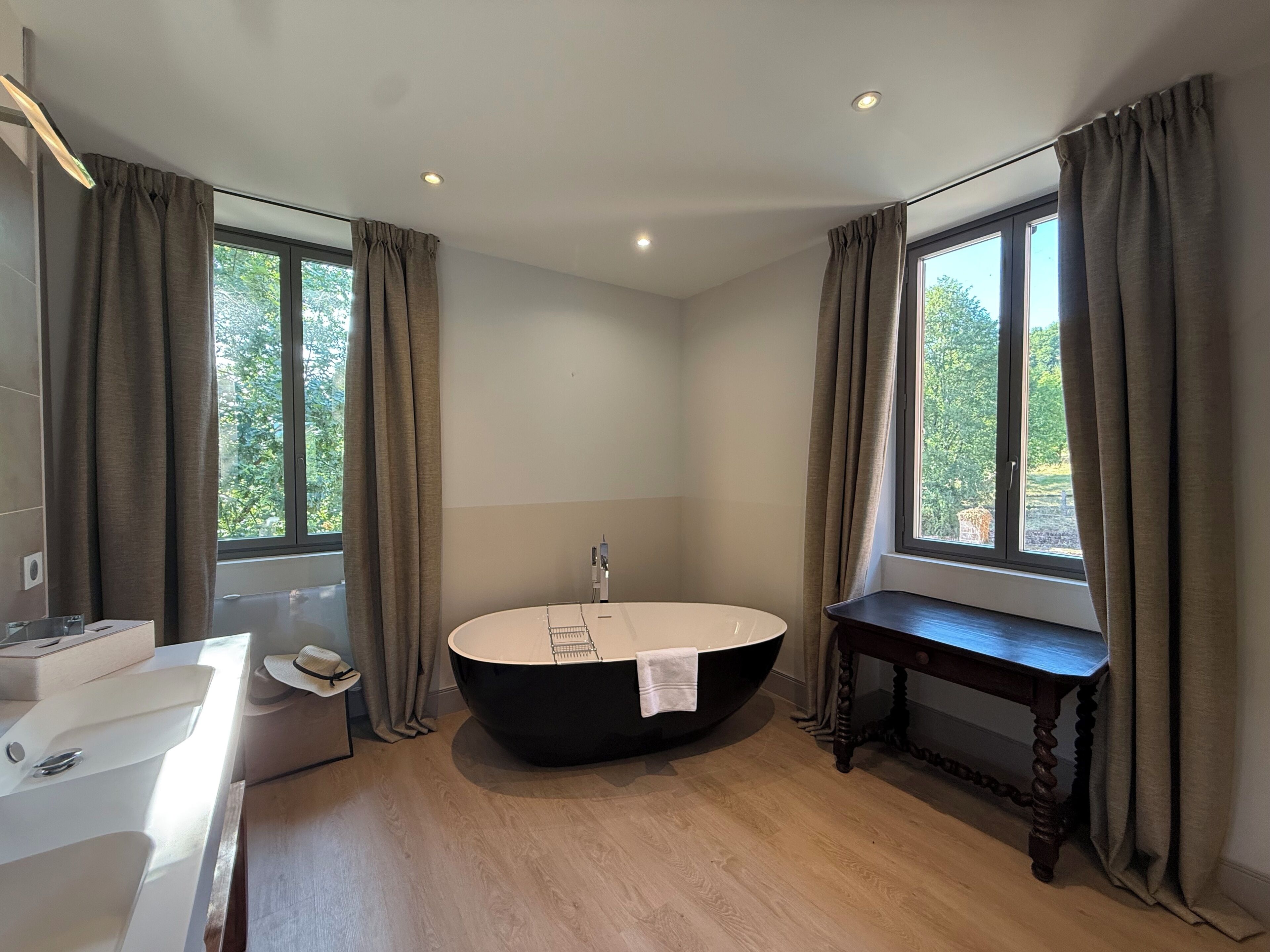 A modern bathroom with a freestanding bathtub, a vanity with a mirror, and a window providing natural light.