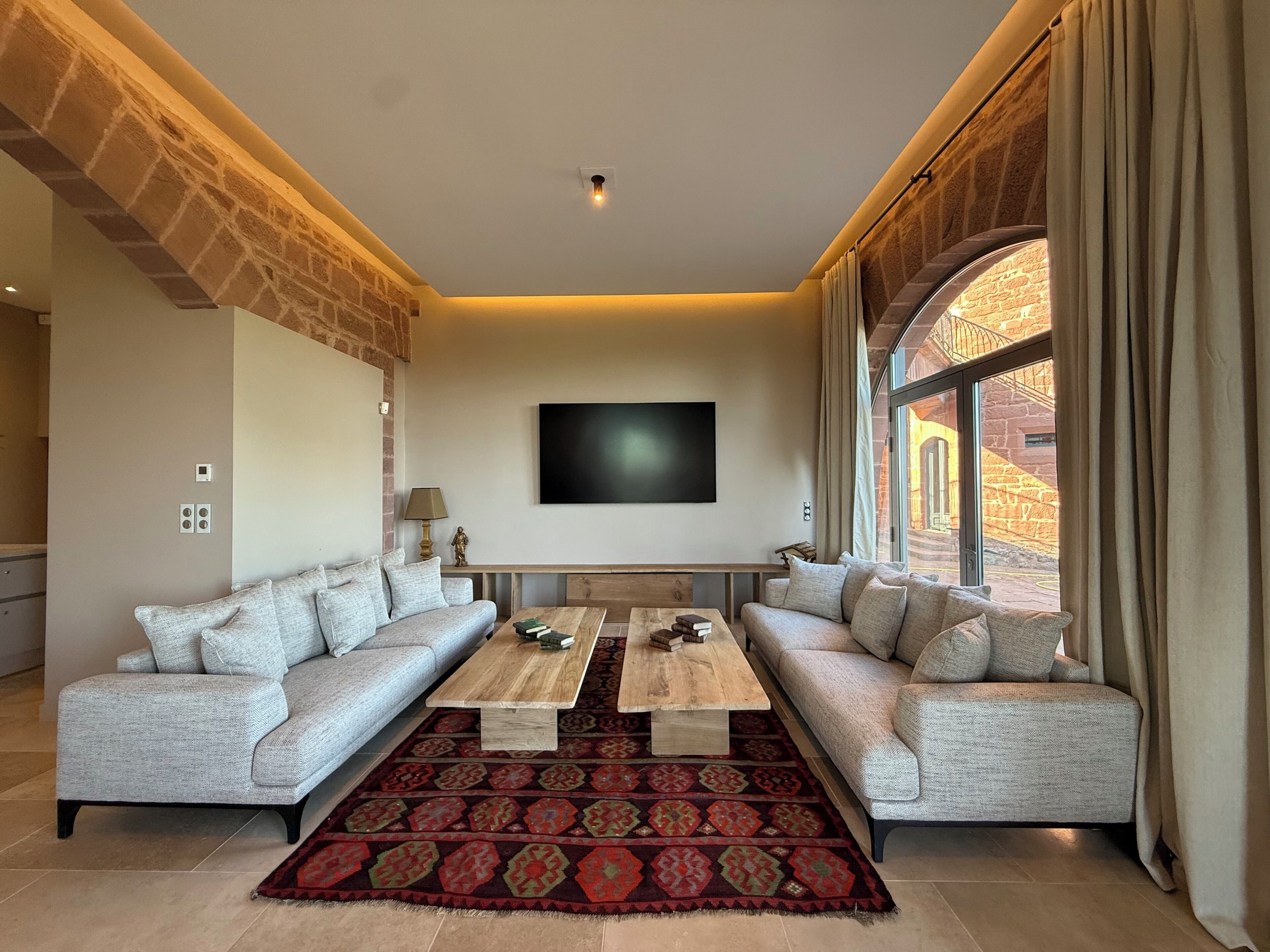A modern living room with two sofas, a coffee table, and a TV mounted on the wall.