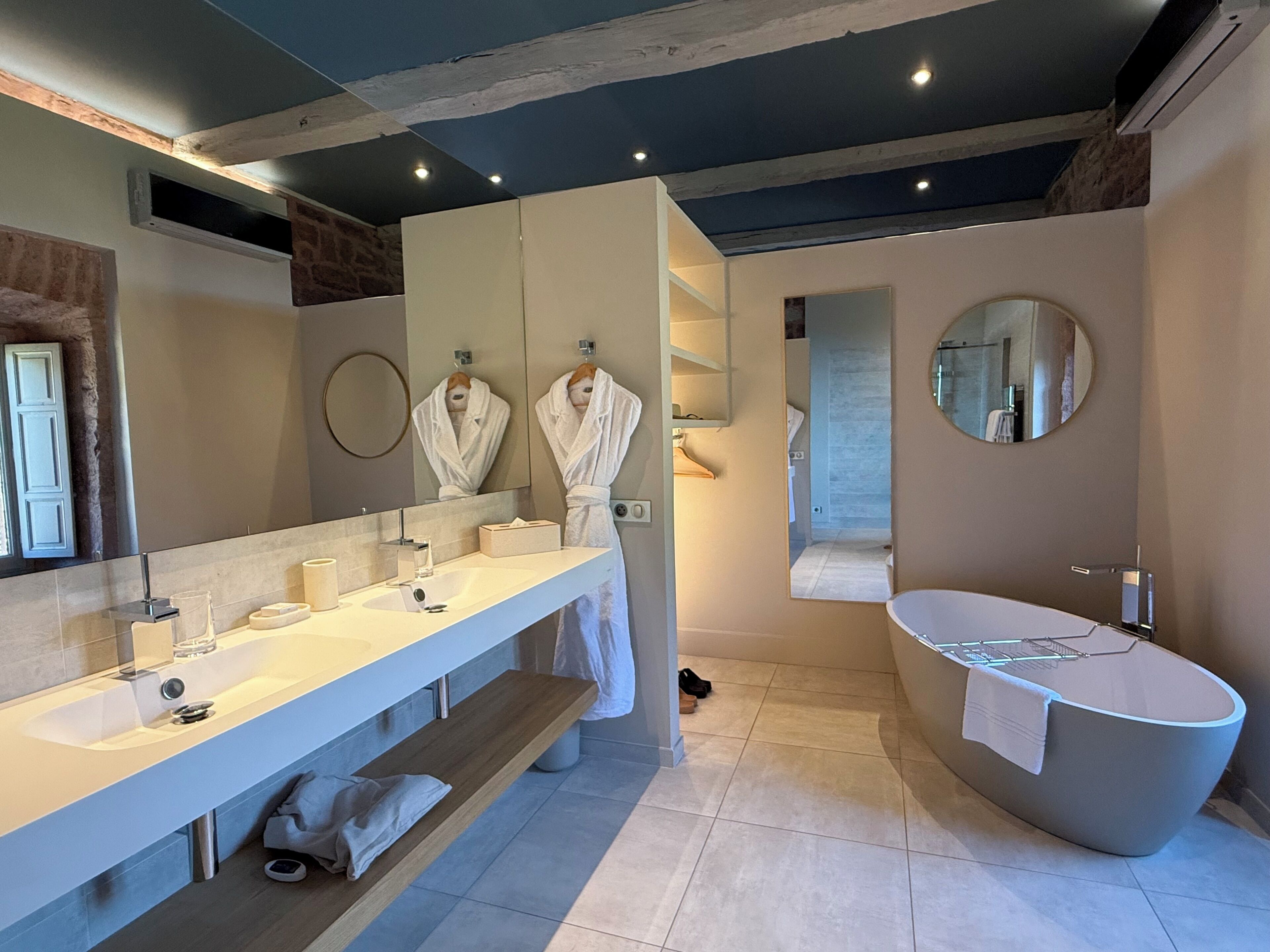 Un baño moderno con un tocador amplio, una bañera independiente y un espejo.