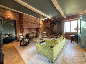 A spacious living room with a fireplace, a sofa, a coffee table, and a bookshelf.