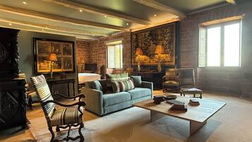 Un salón amplio con un sofá grande, una mesa de centro y una chimenea. Hay varias lámparas y un cuadro grande en la pared.