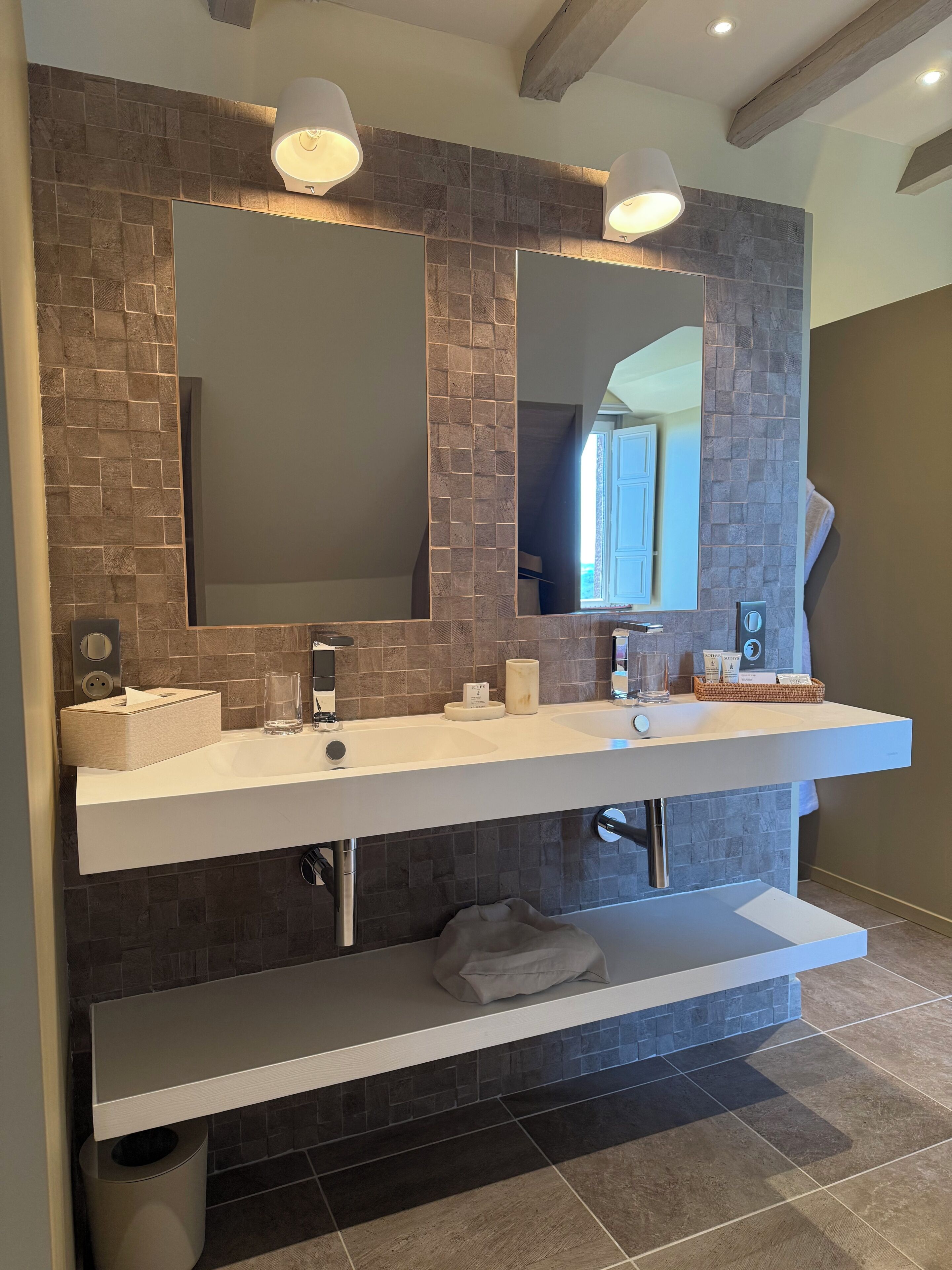 Une salle de bain moderne dotée d’un meuble-lavabo double, de deux miroirs fixés au mur et d’une étagère intégrée.