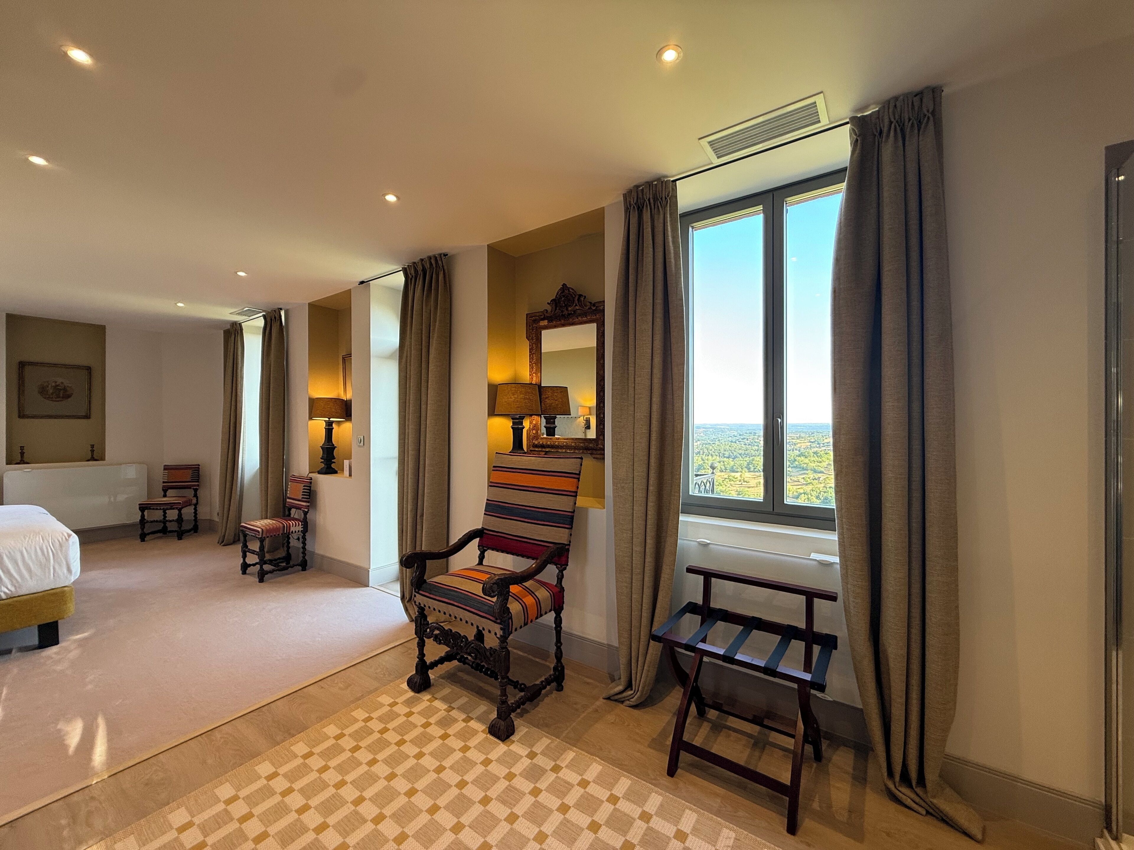 Habitación de hotel con cama, escritorio, silla, ventana con vista y espejo.