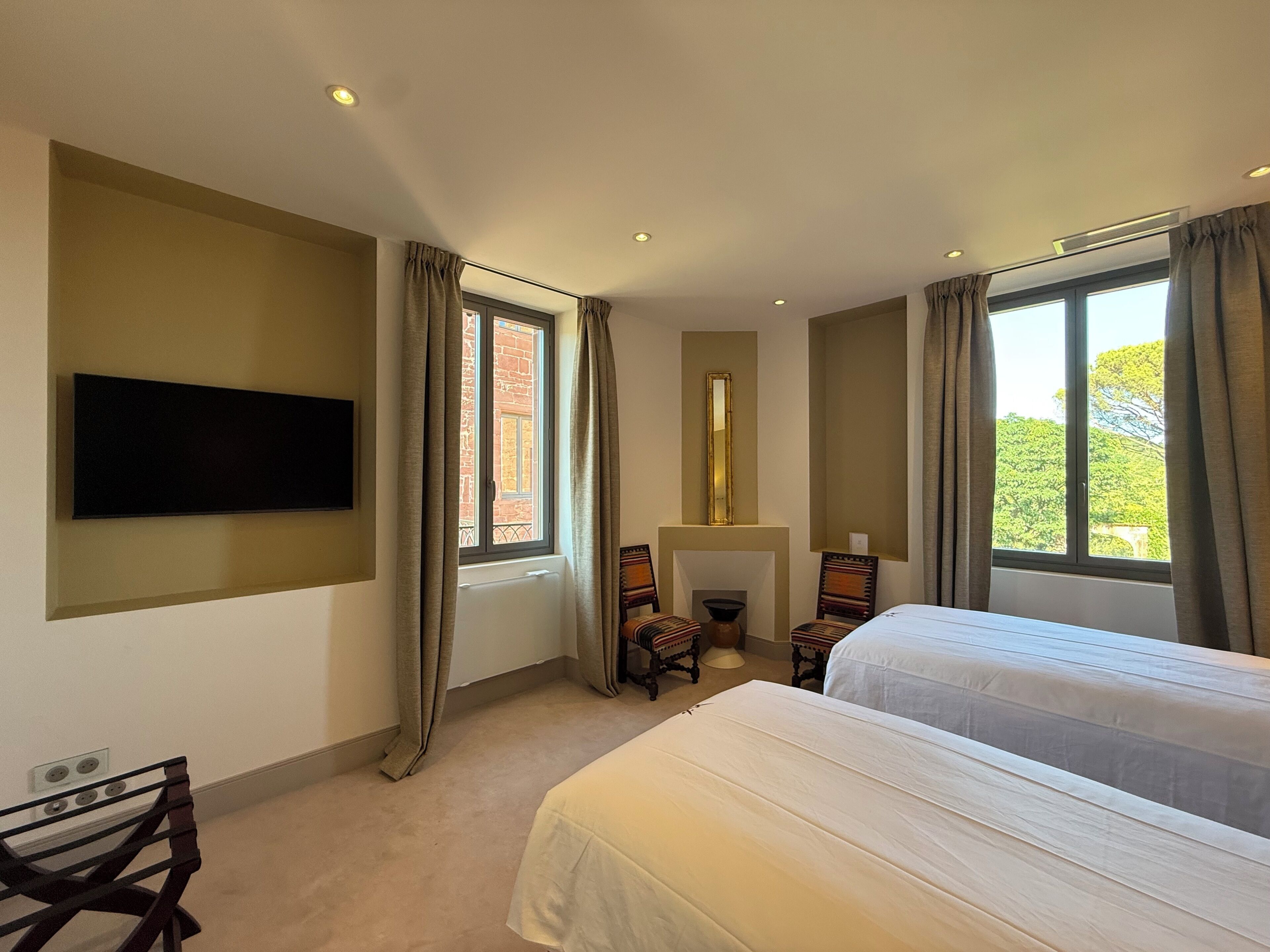 Habitación de hotel con dos camas, televisión de pantalla plana, chimenea y ventanas amplias.