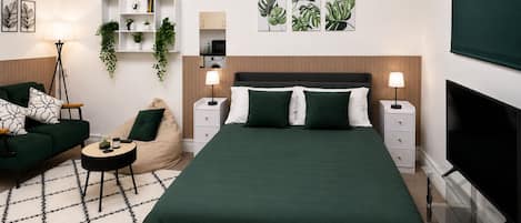 A modern bedroom with a large bed, bedside tables, a sofa, a bean bag, and a TV.