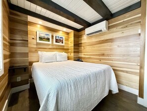 Een kamer met een bed, houten wanden en een airconditioning.