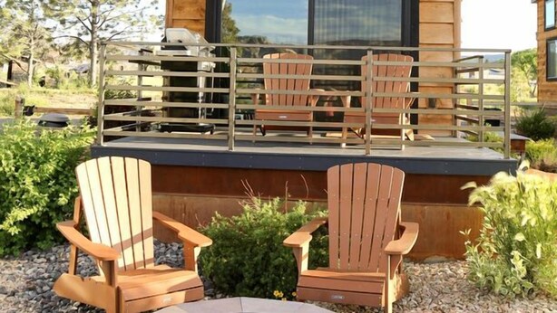 A wooden cabin with a deck, outdoor seating, and a fire pit.