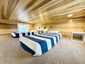 A room with wooden ceiling and walls, two beds with blue and white bedding, a bedside table with a lamp, and a window with blinds. - Escalante Escapes Desert Willow Tiny Cabin Rental (Escalante)