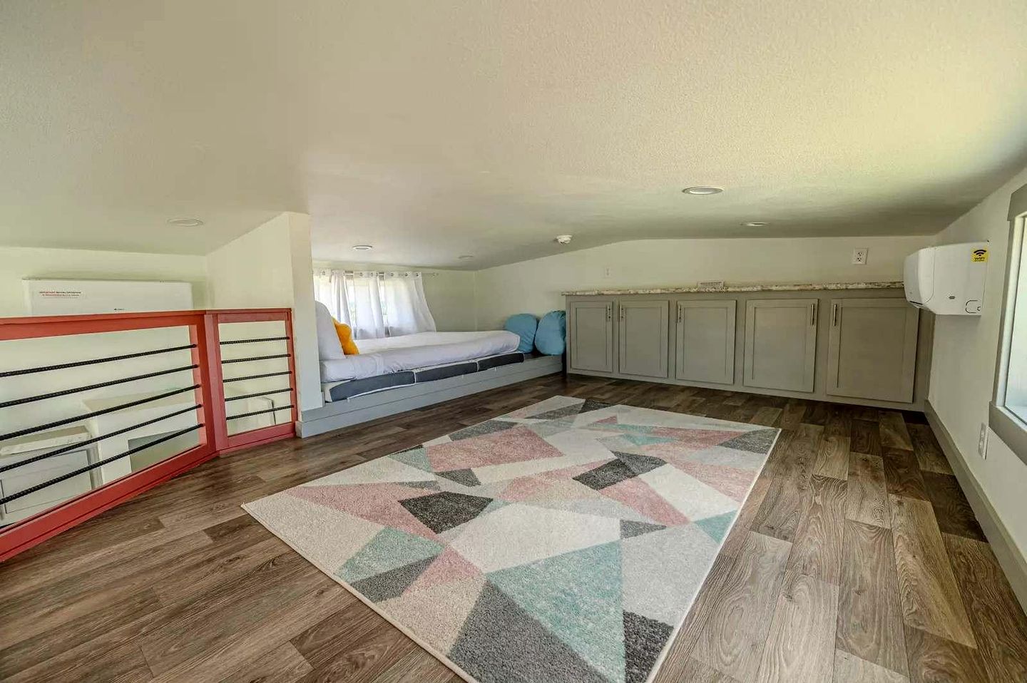 A compact room with a bed, a kitchenette, and a window.