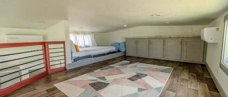A compact room with a bed, a kitchenette, and a window.