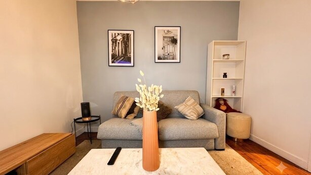 Ein Wohnzimmer mit Sofa, Couchtisch, Blumenvase und Bücherregal.