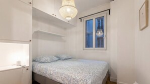 Ein Schlafzimmer mit Bett, Nachttisch, Pendelleuchte und Fenster mit Blick.