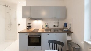 Eine kleine Küchenzeile mit Kaffeemaschine, Spüle und Backofen.